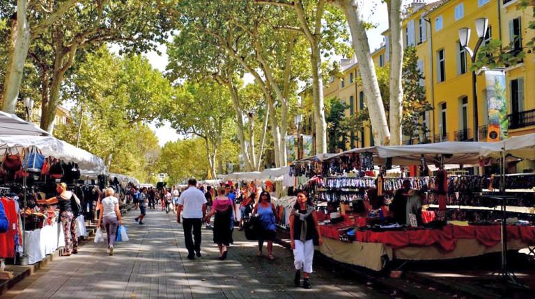 Several people stroll through a street lined with market stalls